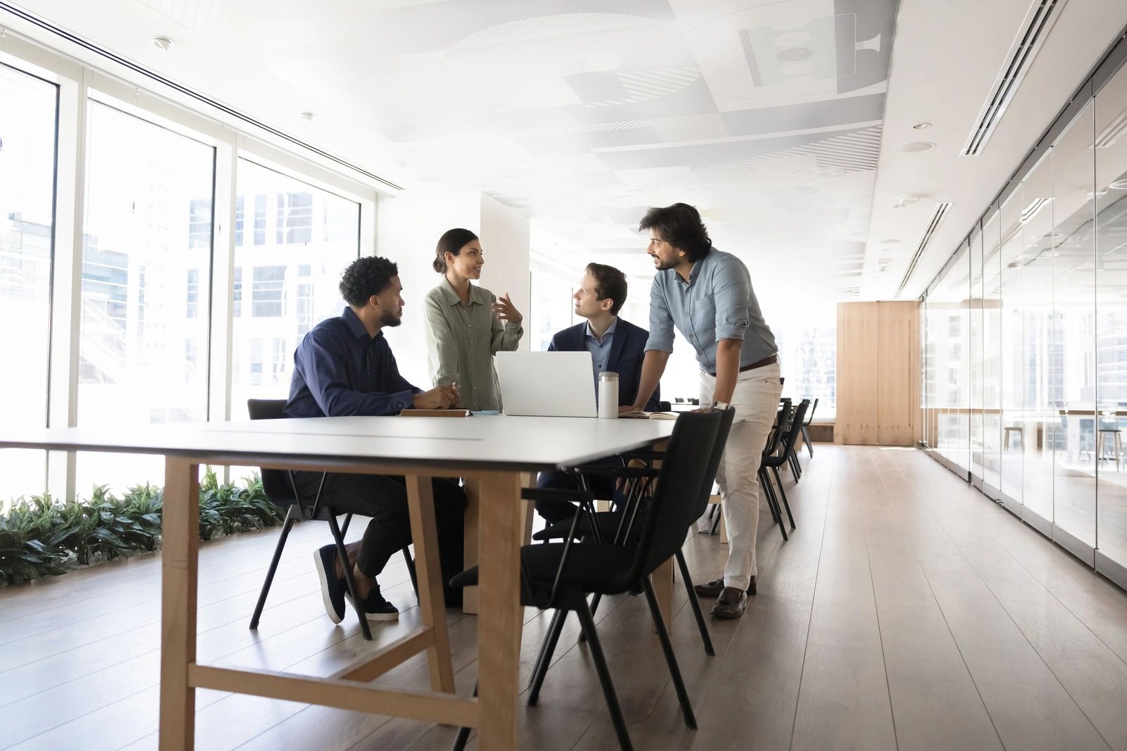Multiethnic coworkers talking at meeting table with laptop